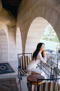 Woman looking away while sitting on railing