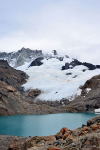 Scenic view of sea and snowcapped mountains against sky