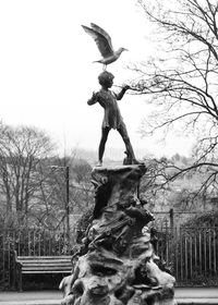 Statue of bird on bare tree against sky