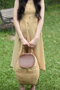 Midsection of woman holding umbrella standing on field