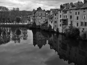 Buildings by calm lake against sky