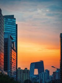 Modern buildings in city against sky during sunset