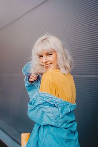 Happy woman standing against wall