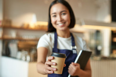 Portrait of young woman using mobile phone at cafe