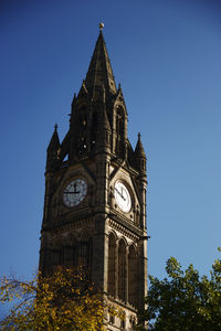 Low angle view of clock tower against clear blue sky