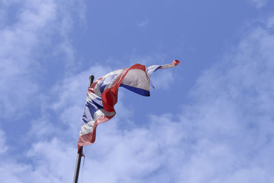 Low angle view of men flag against blue sky