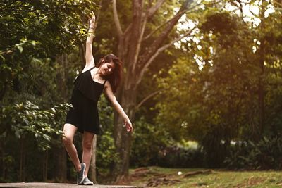 Full length of woman balancing on railing against trees