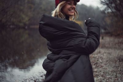 Side view of a smiling young woman in rain