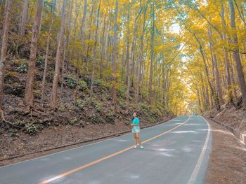 Woman standing on road in forest