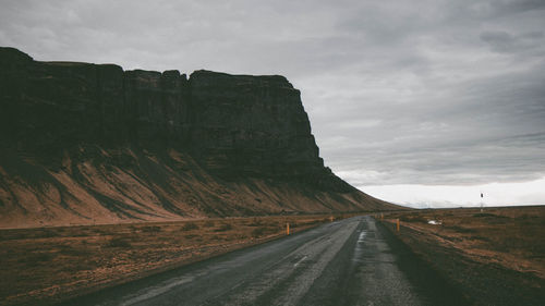 Road leading towards mountains against sky