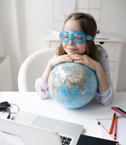 Cute girl with closed eyes and globe at desk