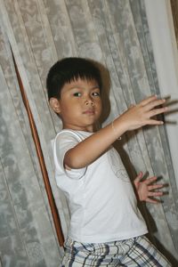 Portrait of boy posing against curtain at home