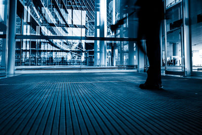 Low section of person walking on footpath by buildings in city