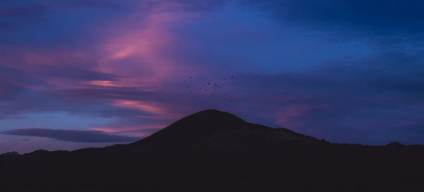 Low angle view of silhouette mountain against sky at sunset