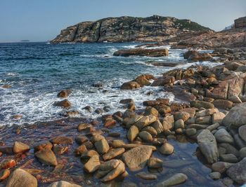 Rocks in sea against clear sky