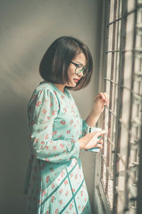 Side view of woman standing by window