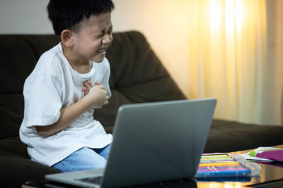 Rear view of boy using mobile phone at home
