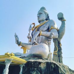 Low angle view of statue against temple against clear sky