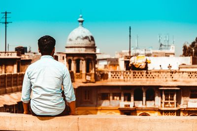 Rear view of man sitting outside temple