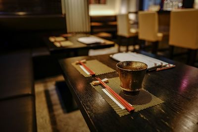 High angle view of drinking glass and chopsticks on place mat over table