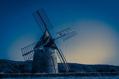 Low angle view of traditional windmill on field against clear blue sky