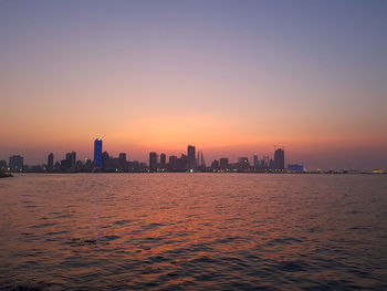 Sea and buildings against clear sky during sunset
