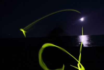 Close-up of illuminated sea against sky at night