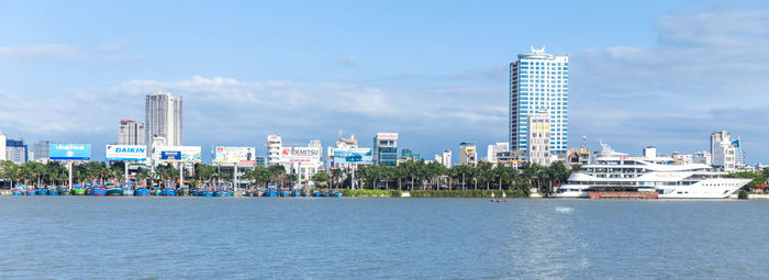 Sea and modern buildings in city against sky