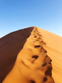 Sand dunes in desert against clear blue sky