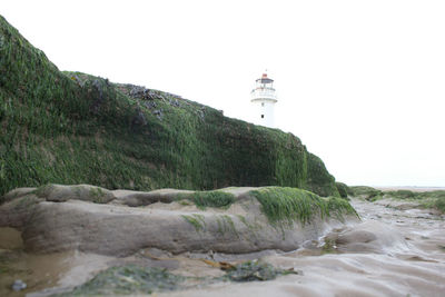 Low angle view of lighthouse by sea against clear sky