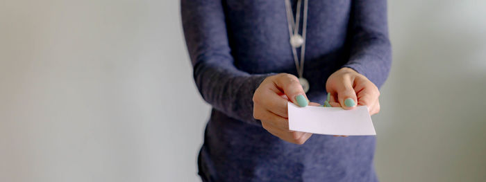 Midsection of man holding paper while standing against wall