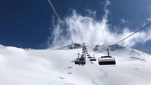 Overhead cable car on snowcapped mountains against sky