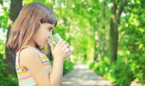 Cute girl drinking water while standing outdoors