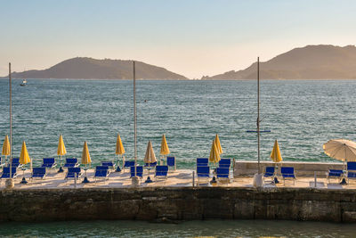 Gulf of poets with deck chairs and sun umbrellas on a pier and the promontory of portovenere