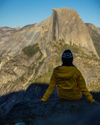 Rear view of woman sitting on rock