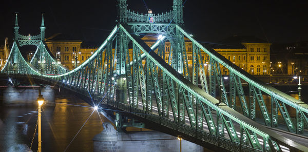 Illuminated liberty bridge over river at night in city