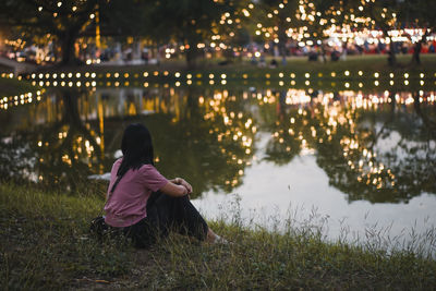 Rear view of woman standing by lake at night