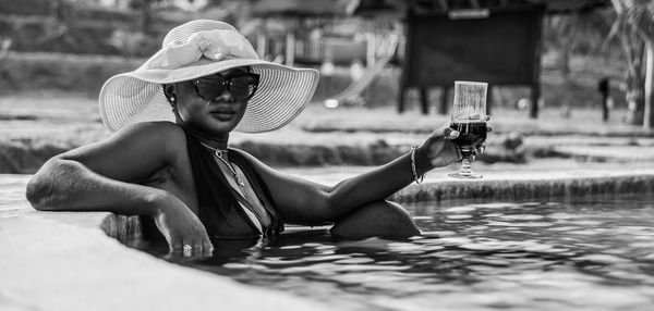 African women with hats sitting and enjoying a glass of wine in the pool