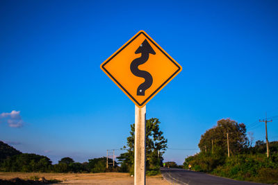 Low angle view of road sign against clear blue sky