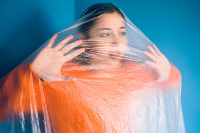 Close-up portrait of young woman against blue background