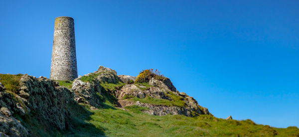 Low angle view of rocks against clear blue sky