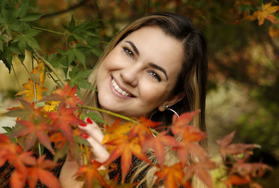 Portrait of smiling young woman by plants during autumn