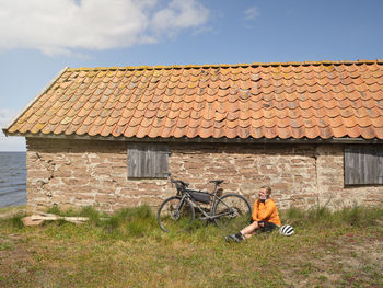 Cyclist relaxing near stone house at sea