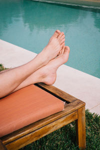 Low section of woman relaxing by swimming pool