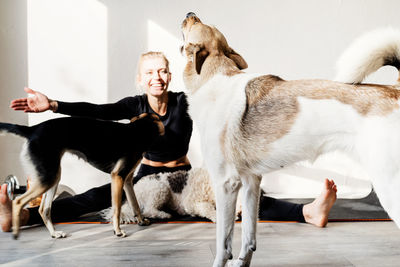 Full length of smiling woman with dog sitting at home