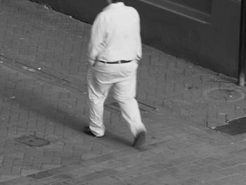 Low section of man walking on cobblestone