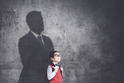 Portrait of boy standing against wall