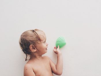 Girl holding seashell against white wall