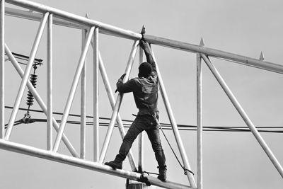 Full length of boy standing on metallic structure against sky