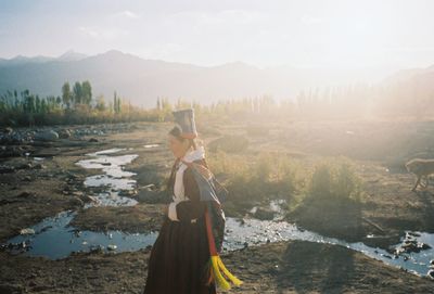 Woman standing on mountain against sky